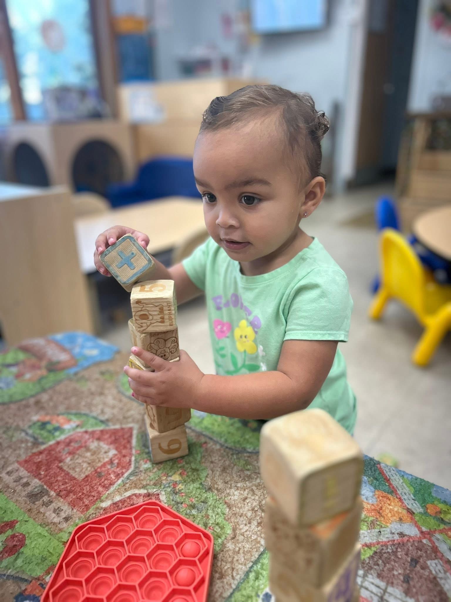 A young child building with blocks in the Caterpillars classroom