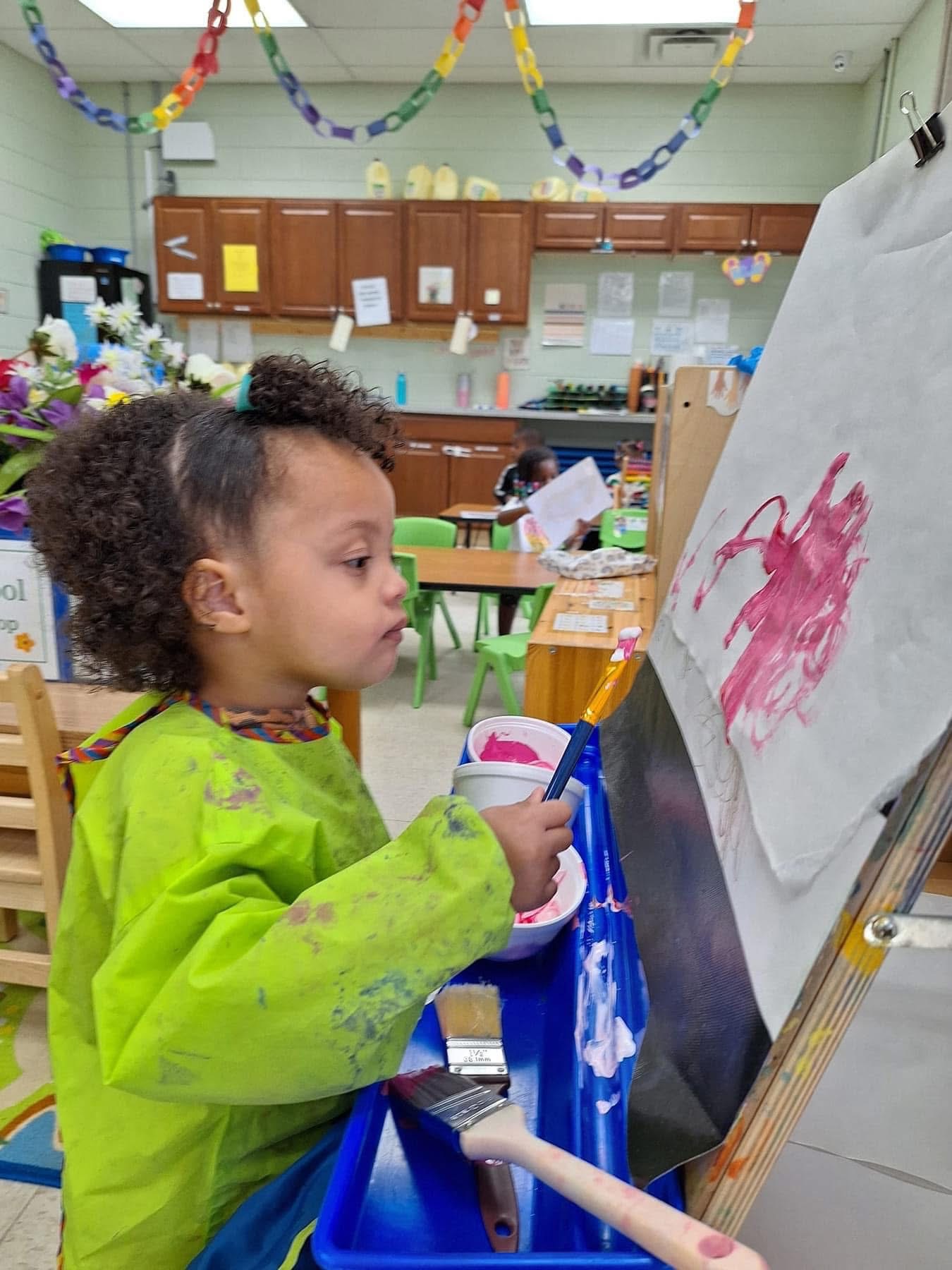A child paints at an easel during a classroom art activity.