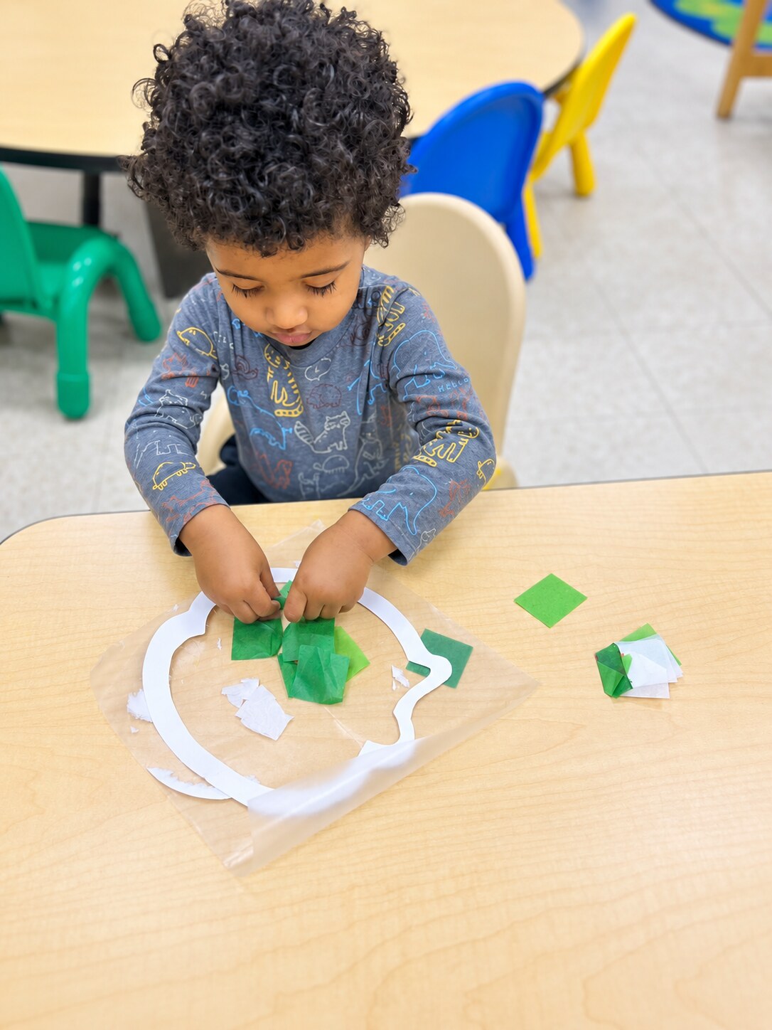 A child places materials onto a classroom project.