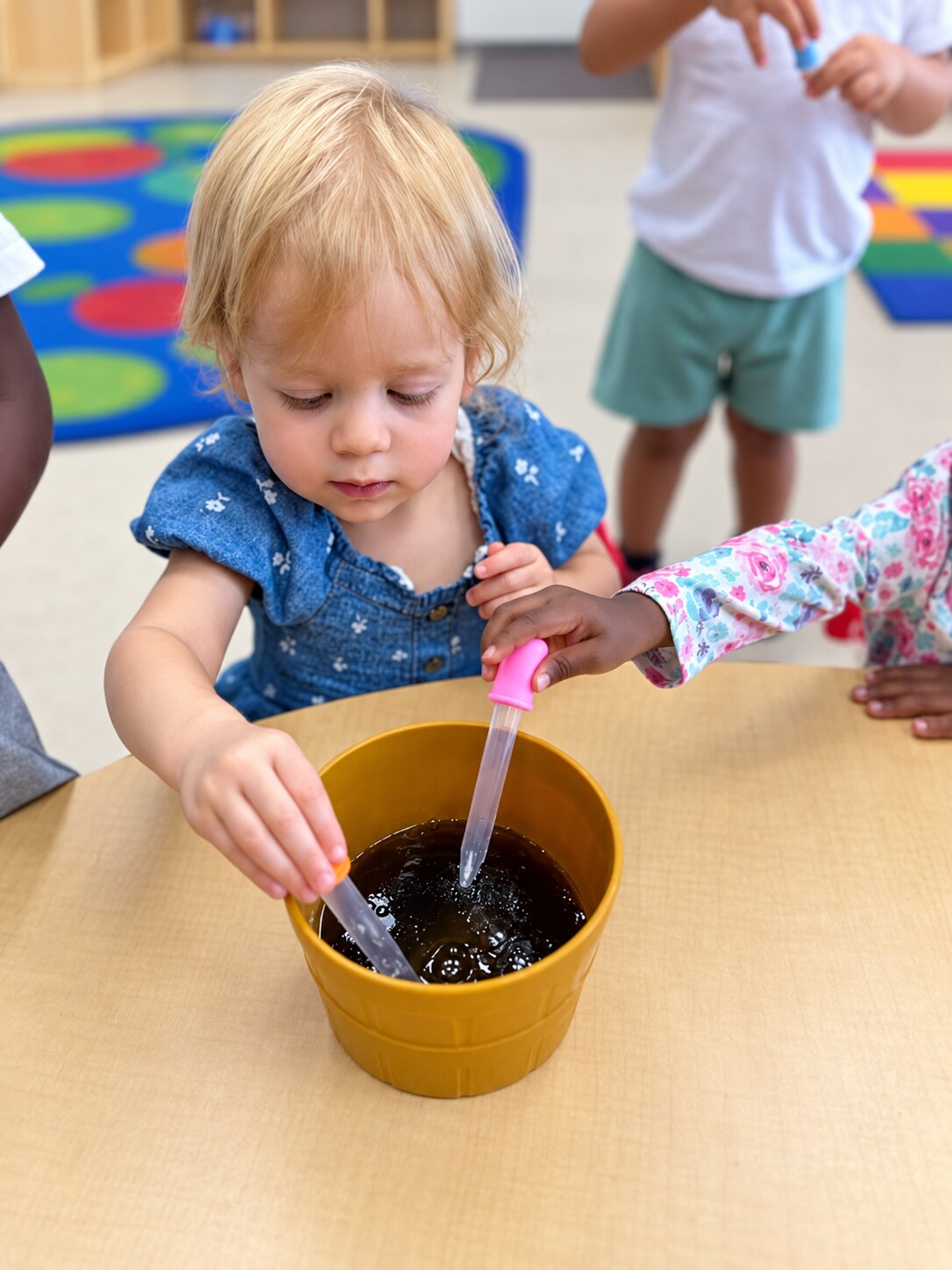 A toddler stirs and mixes materials during pretend play.