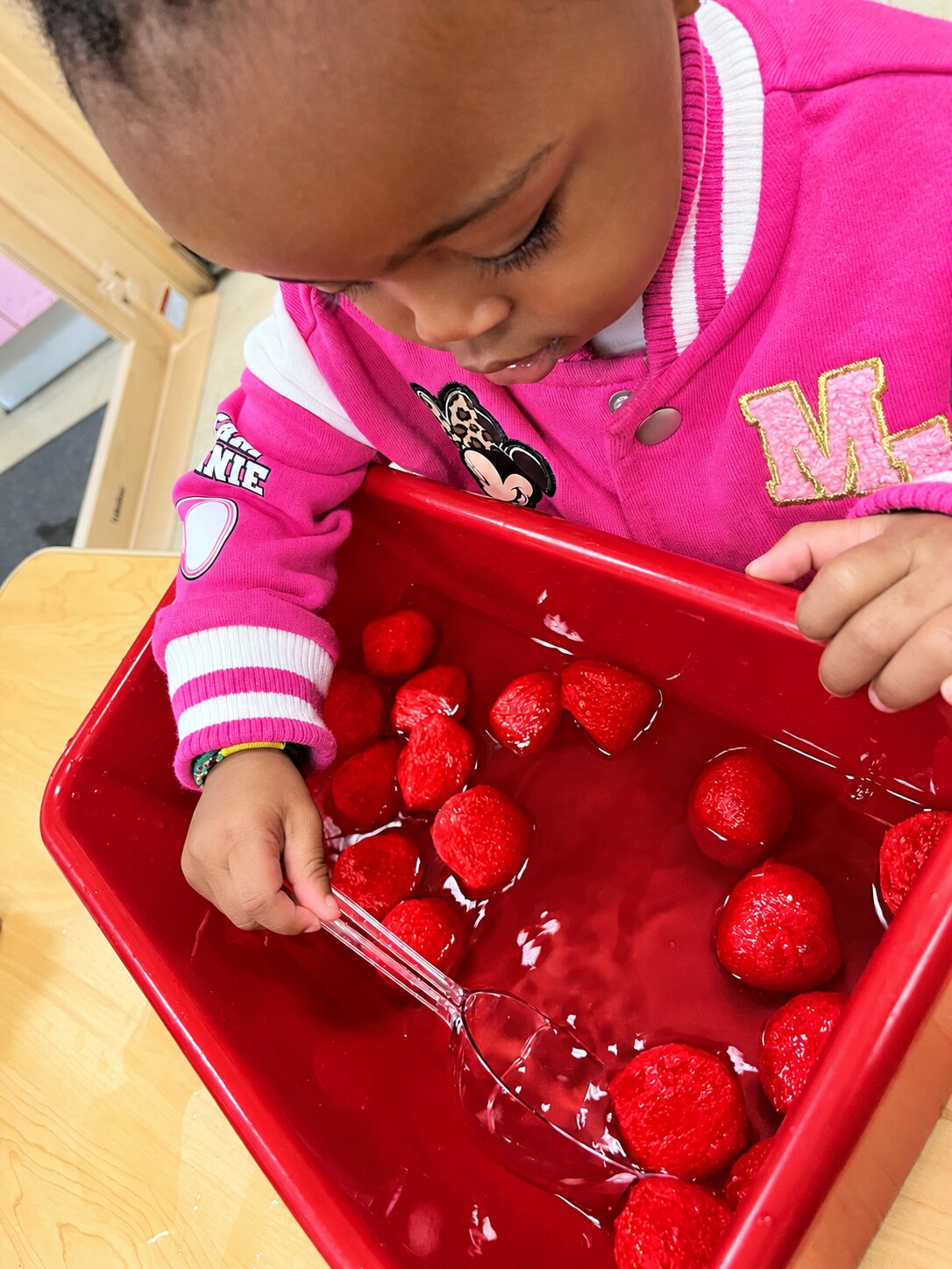 A child investigates a sensory bin with both hands.