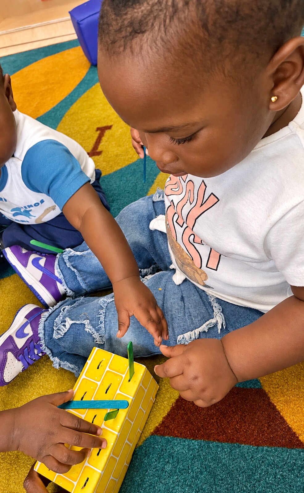 A child explores small materials at the classroom table.