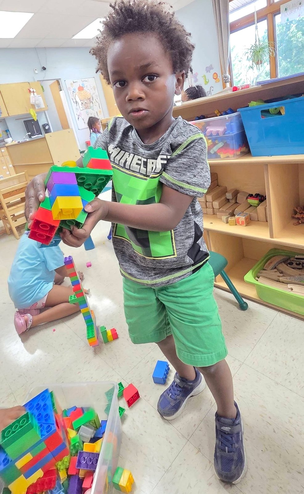 A child carries colorful blocks during building play.