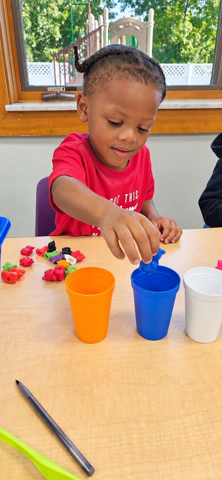 A child explores sorting cups and early math materials.