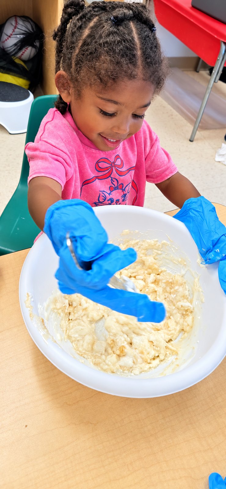 A child explores a tactile sensory activity with bowls and tools.