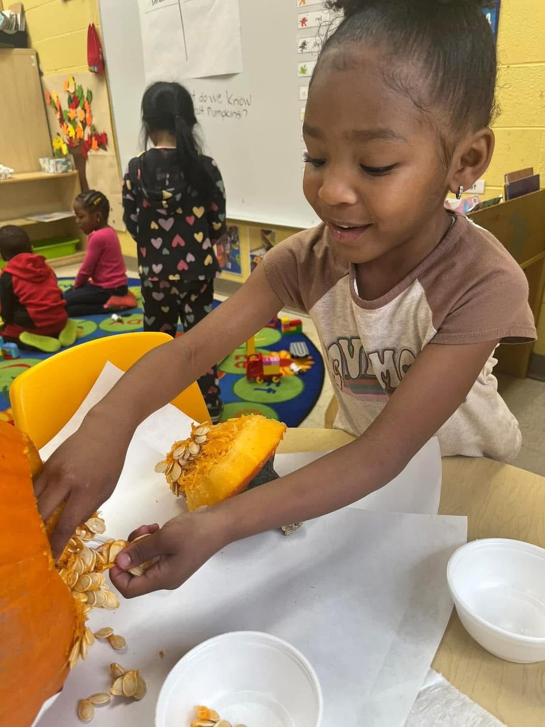 A child prepares and explores materials at a sensory table.