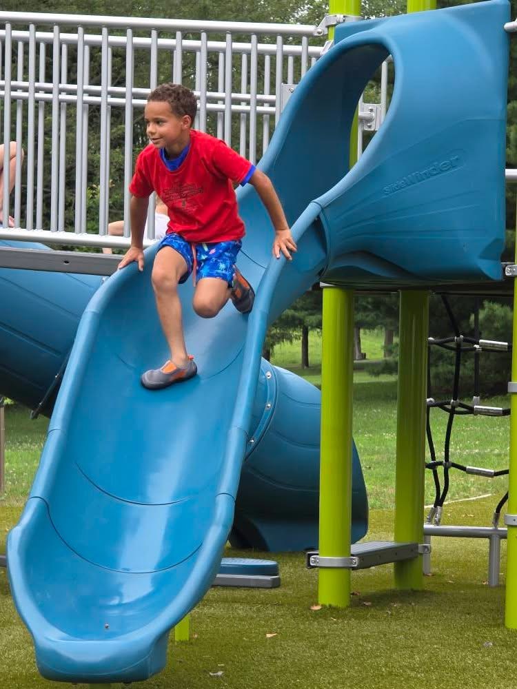 A school-age child enjoys an outdoor playground slide.