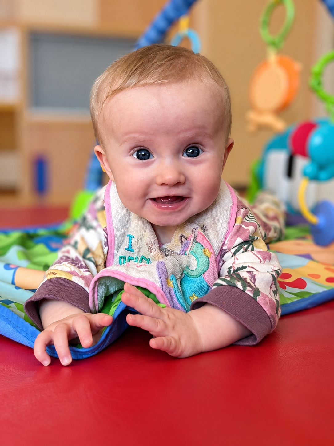 An infant lifts their head and looks around during tummy time.